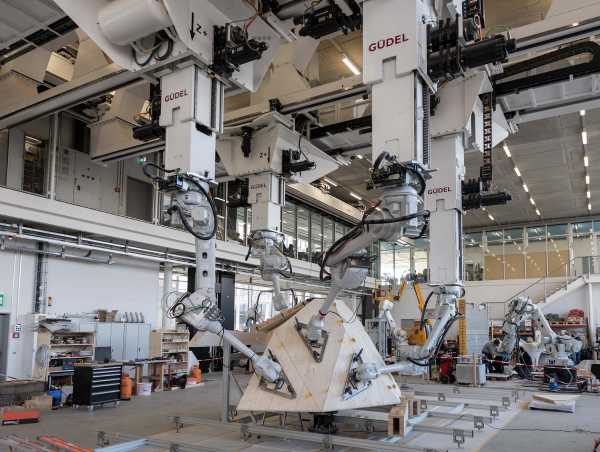 Roboterarme halten Holzplatten in einer Fertigungshalle
