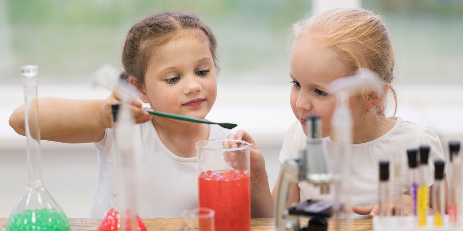 Zwei junge Mädchen experimentieren mit einem Reagenzglas