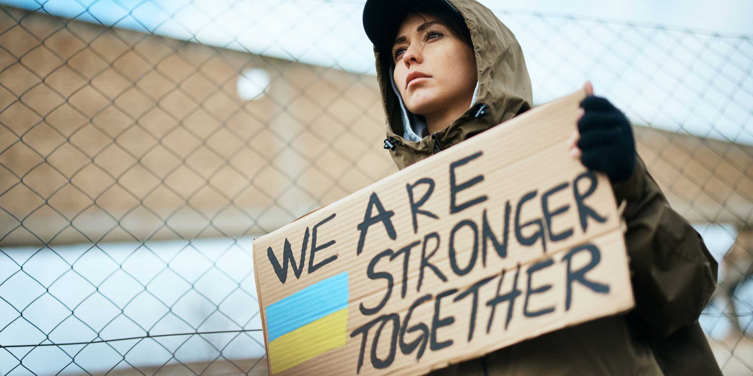 Eine ukrainische Demonstrantin hält ein Pappschild auf dem "We are stronger together" steht