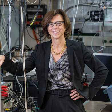 Ursula Keller lachend vor Geräten in ihrem Labor