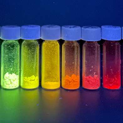 Kleine Gläschen mit fluoreszierenden Substanzen. Diese leuchten in Regenbogenfarben.
