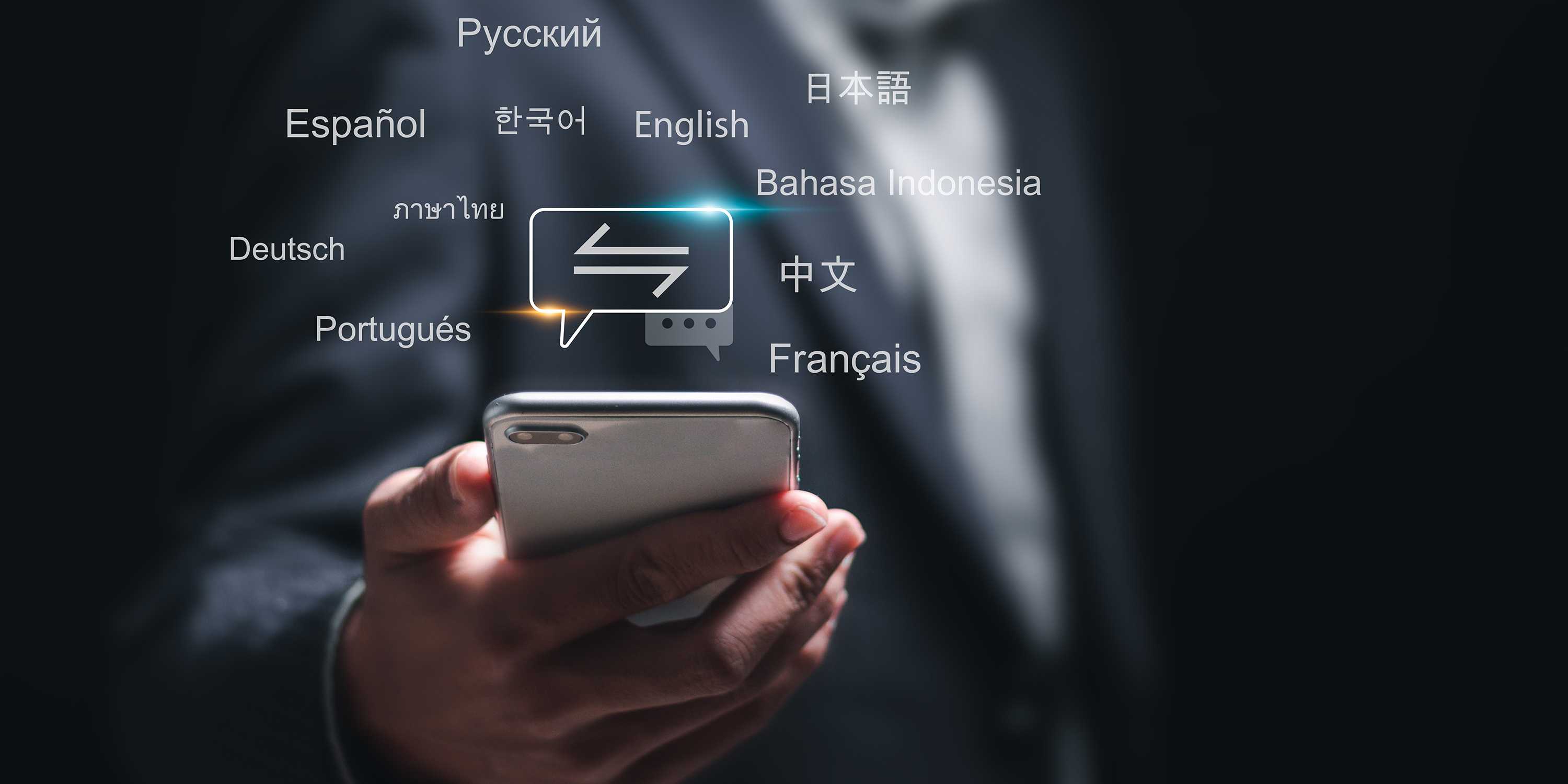 Hand die ein Smartphone hält, in der Luft darüber erscheinen Worte in unterschiedlichen Sprachen