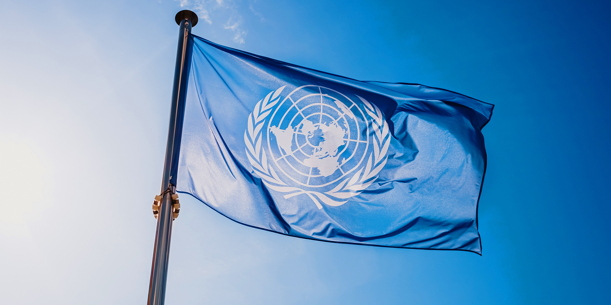 Flagge der UN vor blauem Himmel