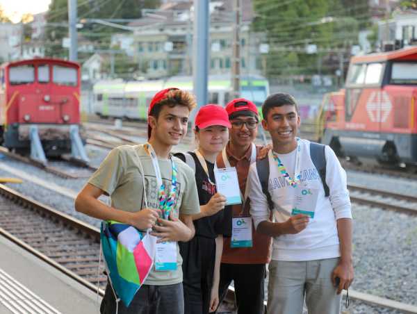 Vier Teilnehmer bei einem Gruppenfoto am Bahnhof.