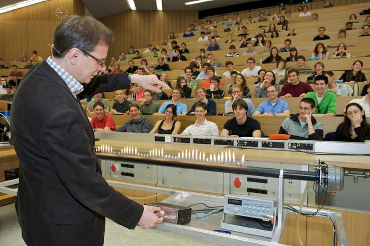 Vergr?sserte Ansicht: Ein Professor führt im Hörsaal Experiment durch. Studierende schauen ihm von den Bänken aus zu.