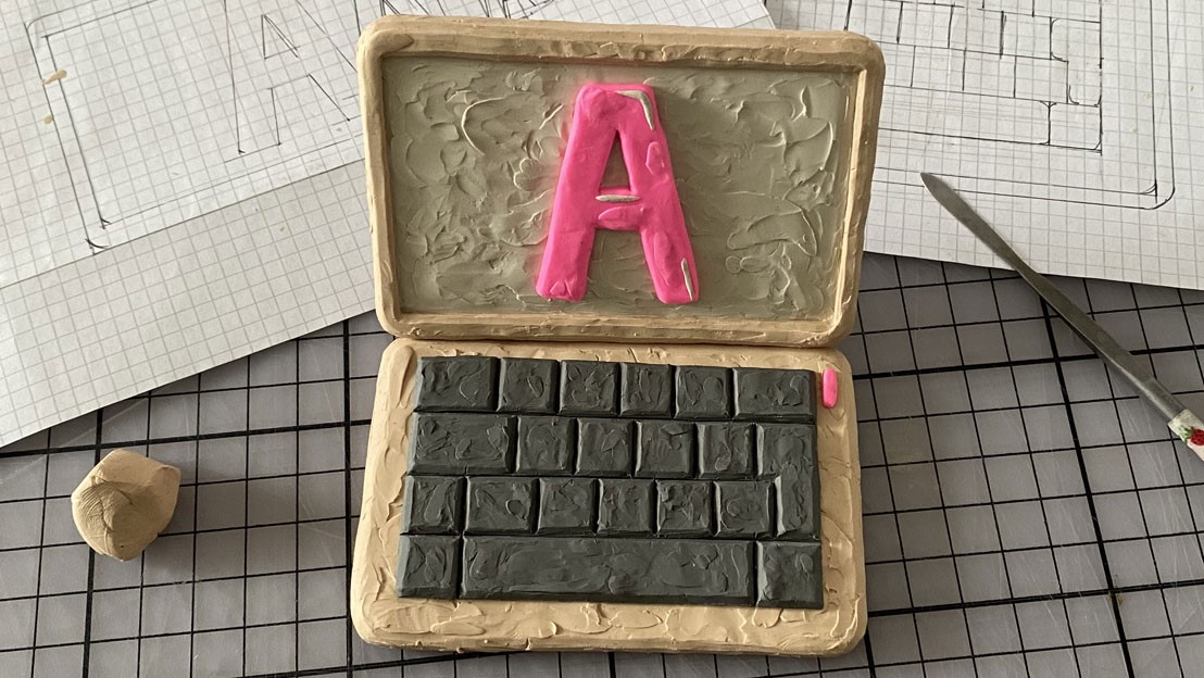Ein Laptop aus Plastilin-Knete mit einem "A" in sehr grosser Schriftgrösse.
