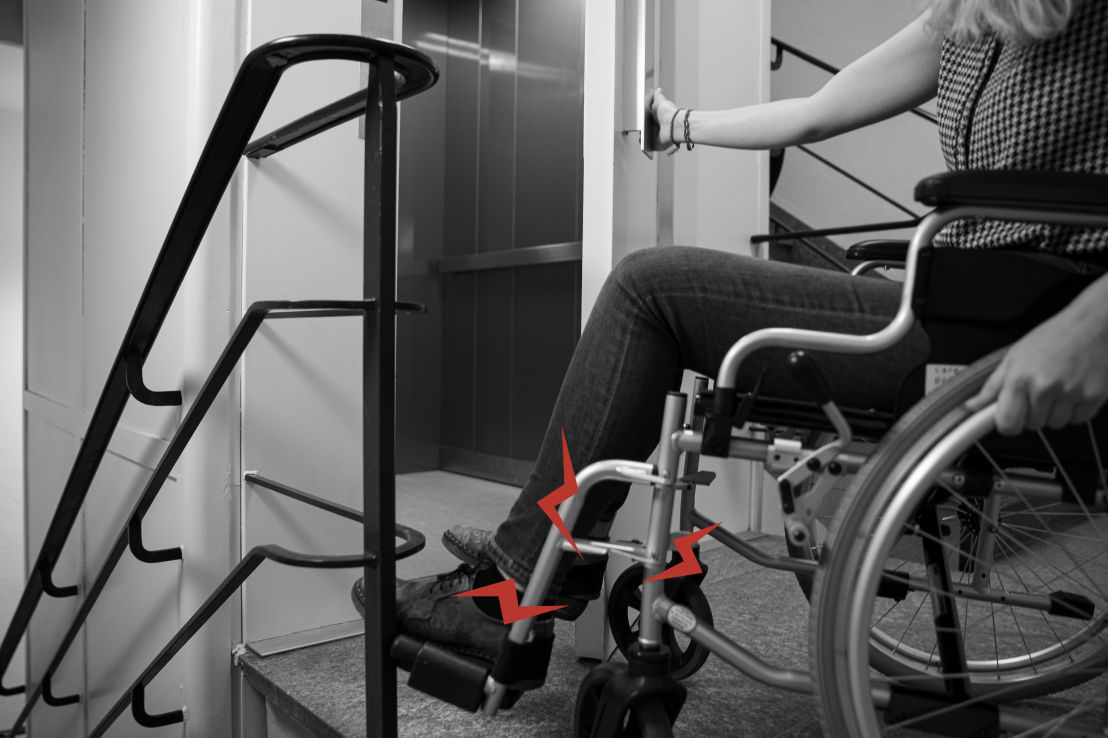 Vergr?sserte Ansicht: Eine Person im Rollstuhl kann eine alte Aufzugtür nicht öffnen, da diese mit dem Rollstuhl kollidiert. 