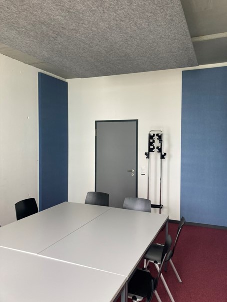 Vergr?sserte Ansicht: Sitzungszimmer, ausgestattet mit einem grauen Deckensegel und blauen Wandabsorbern in drei Ecken des Raumes.